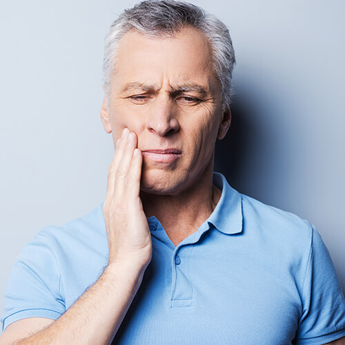 A man holding his jaw with tooth pain