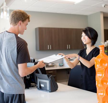 Staff member of Night & Day Dental, a North Carolina dentist office, handing a patient their forms